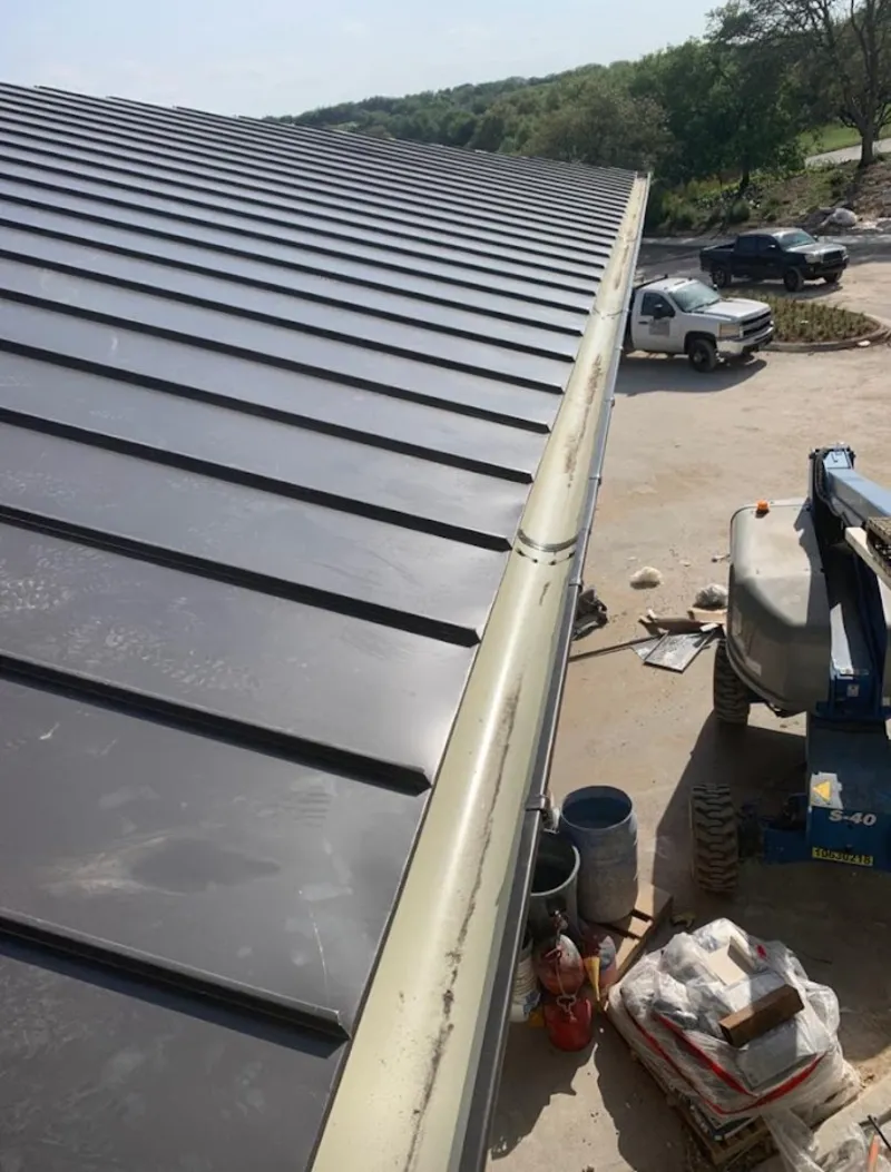Standing seam panel and gutter detail on a metal roofing jobsite in Raleigh